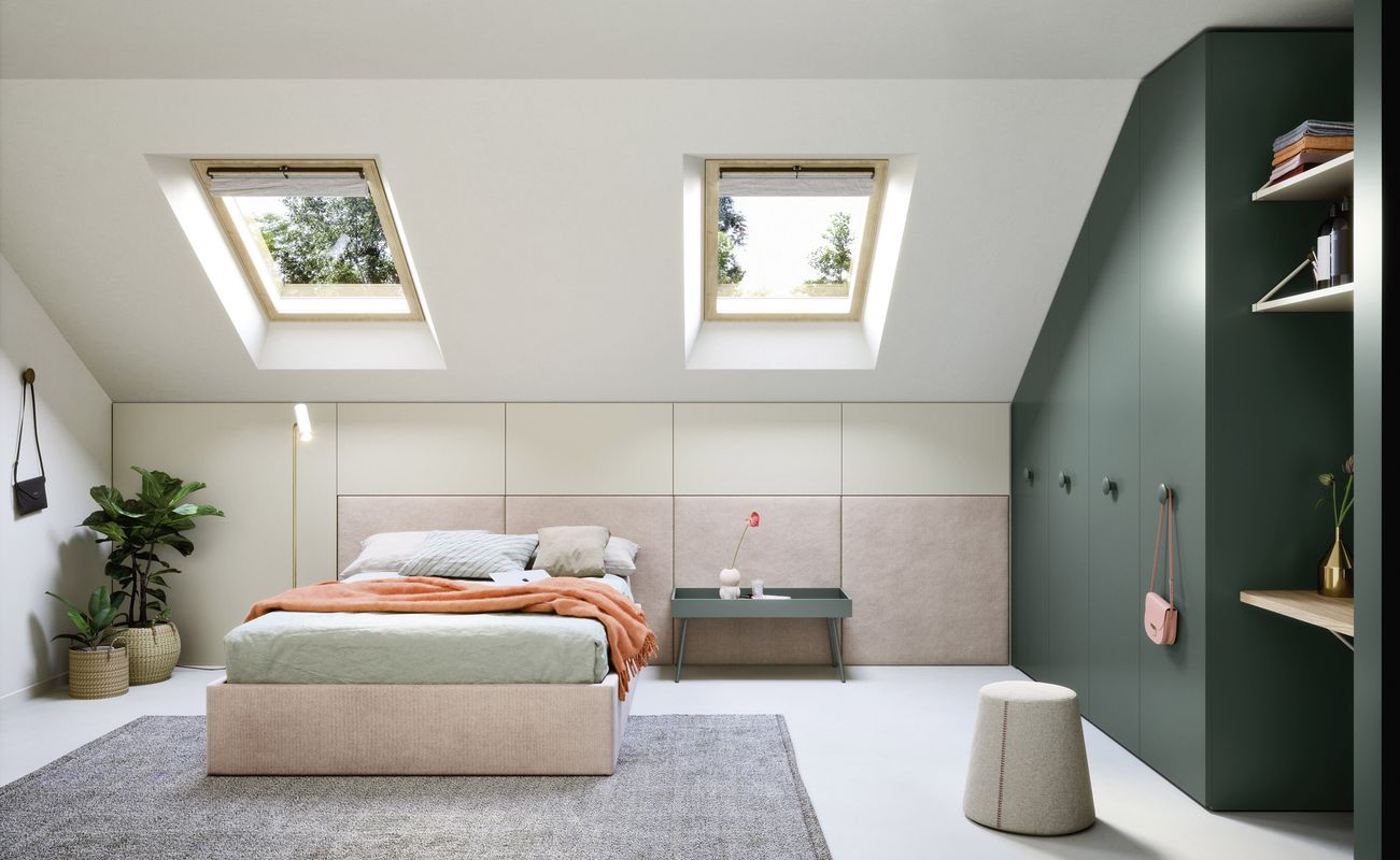Helles Schlafzimmer mit Dachfenstern, einem Bett, einem Tisch und einem Kleiderschrank. Pflanzen und Teppich ergänzen die Einrichtung.